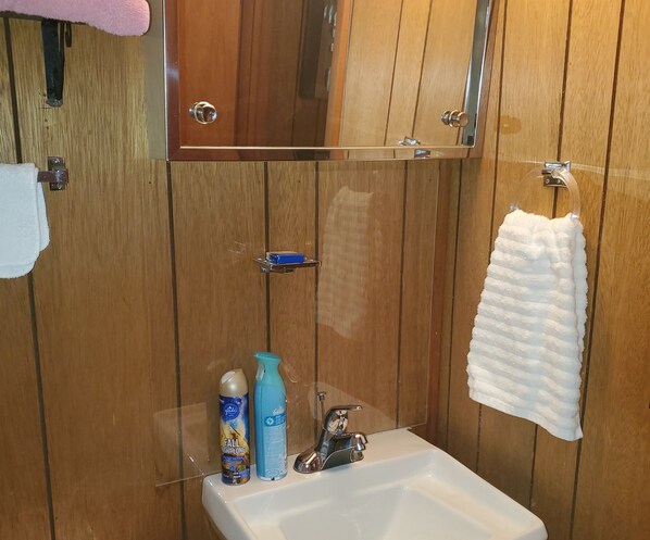 A wooden-paneled bathroom with a sink, a mirror, and a towel hanging on the wall.