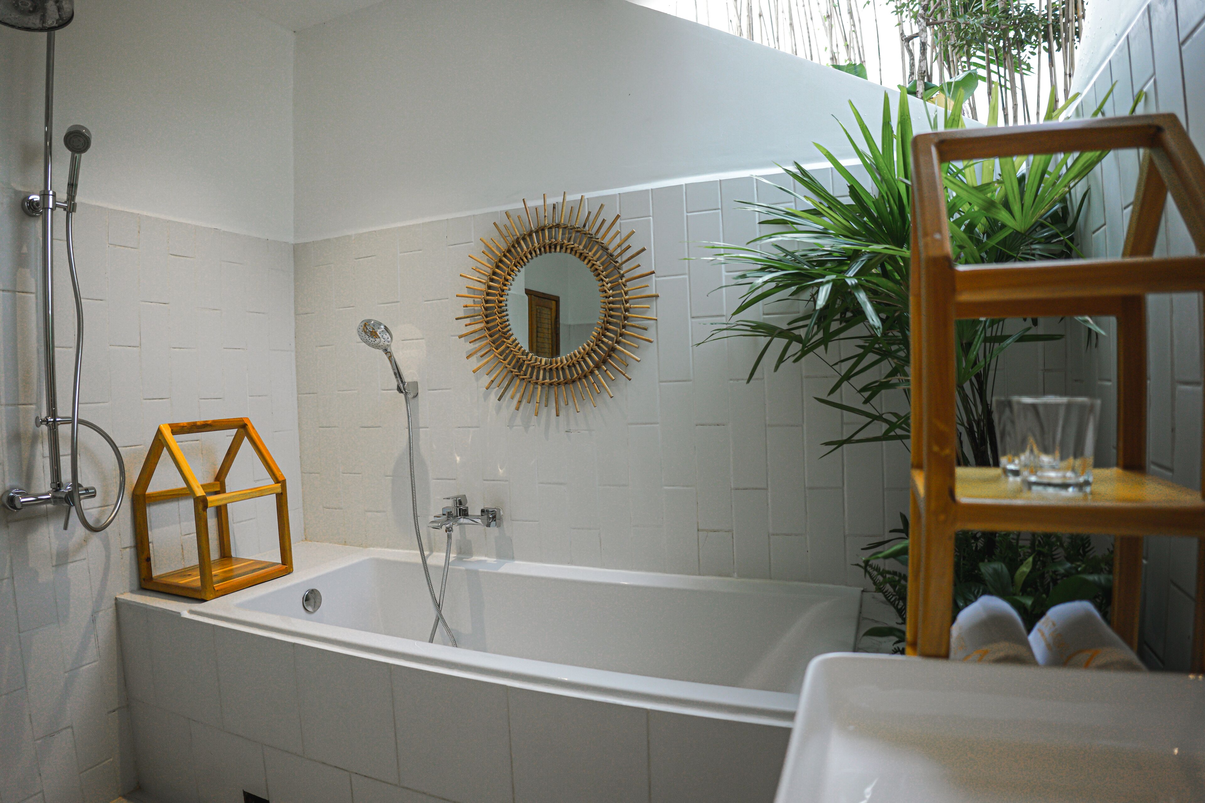A bathroom with a bathtub, a wooden-framed mirror, and a shower.
