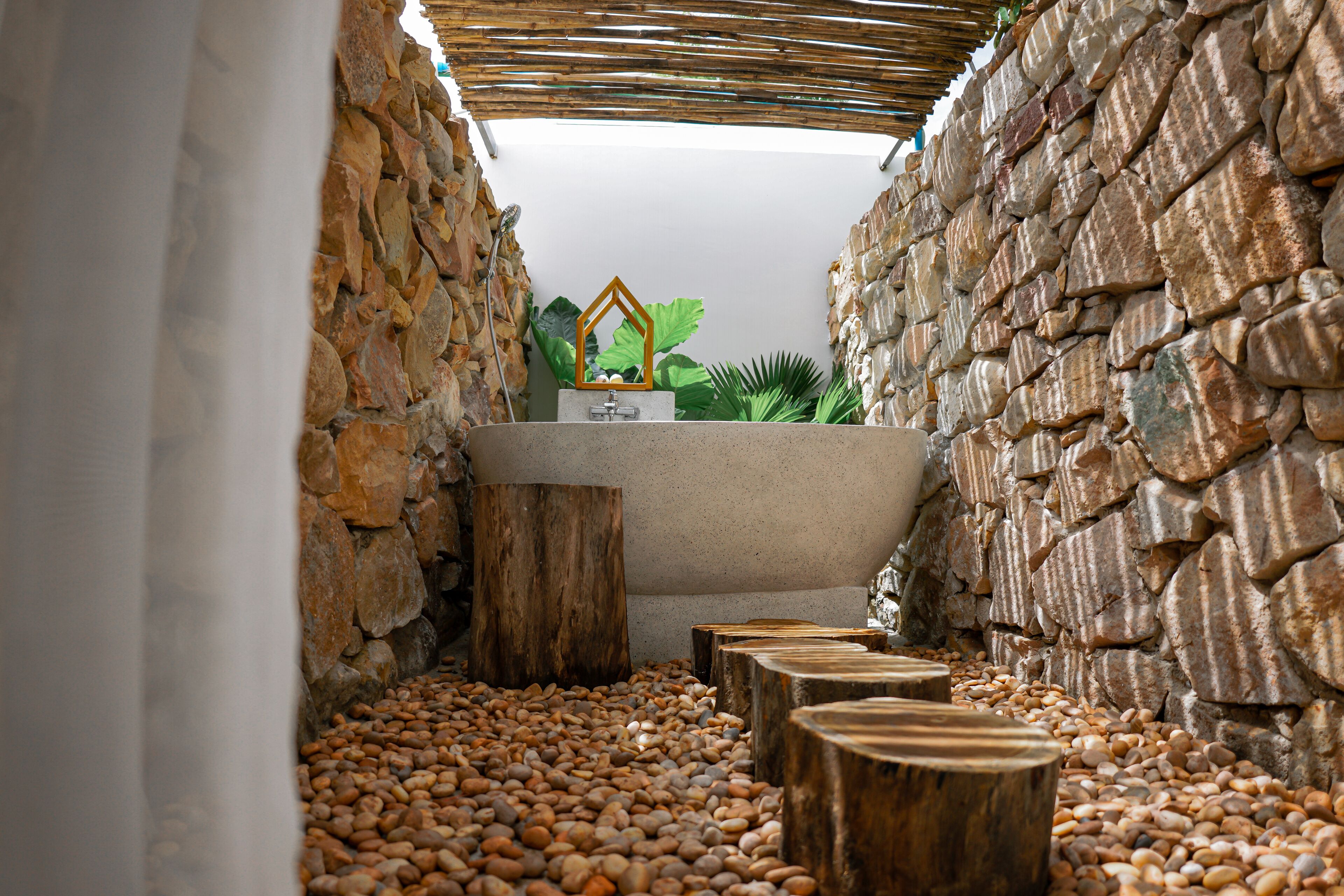 Un espace de détente aux murs de pierre, avec un banc en bois et une petite fontaine.