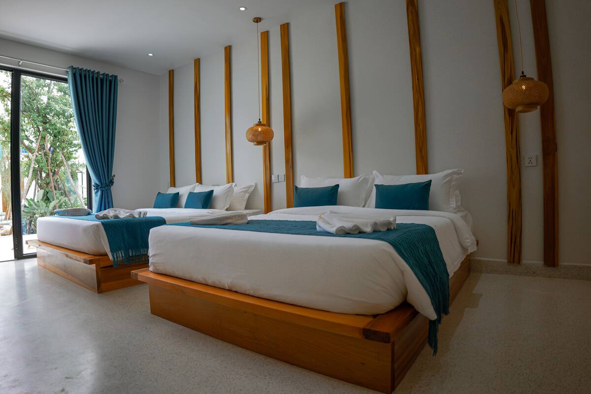 A modern hotel room with two wooden beds, a large window with curtains, and a wooden wall paneling.