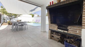 A patio area with a brick fireplace, outdoor seating, and a pool. - Vacation home Aeris by Interhome (Cunit)