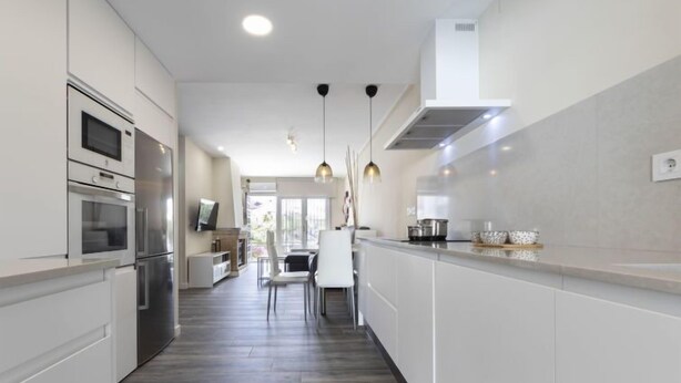 A modern kitchen with white cabinetry, stainless steel appliances, and a long countertop. - Vacation home Aeris by Interhome (Cunit)