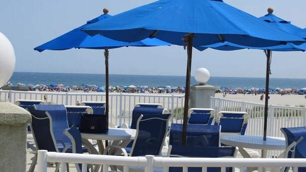 A beachside seating area with blue umbrellas and white railings. - Beachfront  top flr 1 br condo at Summer Sands (Wildwood)