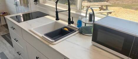 Una cocina con un lavamanos doble, un microondas y un ventanal con vistas a un jardín.
