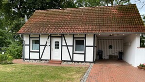 Ein traditionelles Fachwerkhäuschen mit Ziegeldach, einem Backsteinweg, der zum Eingang führt, und einem kleinen Vorgarten.
