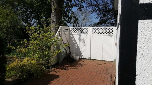 A gated area with a brick pathway leading to a white building.
