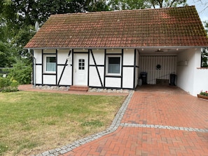 A traditional half-timbered house with a tiled roof, a brick pathway leading to the entrance, and a small front garden.