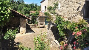 Un edificio de piedra con encanto rústico, con un pequeño porche y una escalera de piedra que lleva a una puerta.