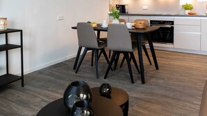Et moderne køkken med spiseplads, der inkluderer en lysekrone, et billede og en kaffemaskine.