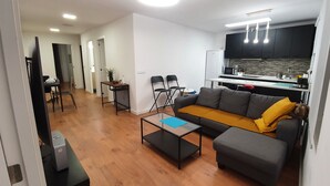 A modern living room with a sofa, coffee table, and a kitchen area with a refrigerator, microwave, and cabinets. - Lighthouseflat next the Marina  (Vilanova i la Geltrú)