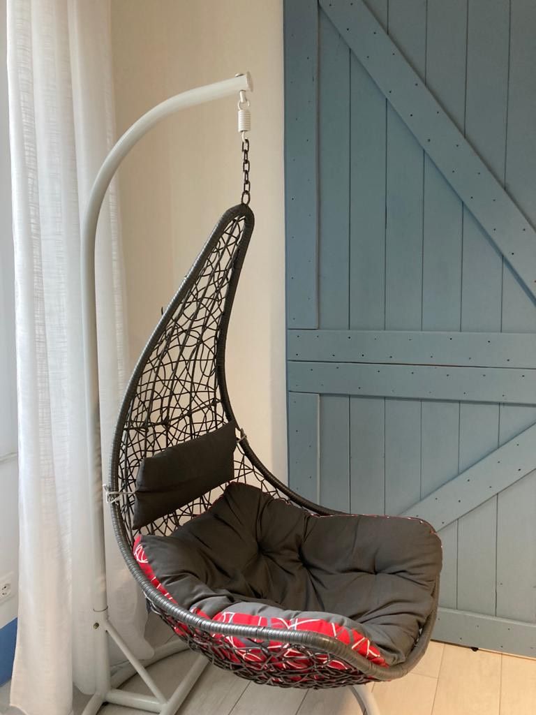 A hanging chair with a geometric design, a cushioned seat, and a chain support.