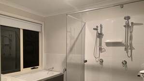 Ein modernes Badezimmer mit einer Duschkabine, einer Badewanne und einem Waschtisch mit Fenster.