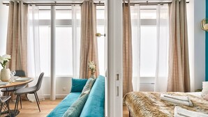 Une chambre d’hôtel moderne dotée d’une grande fenêtre, d’un canapé, d’un lit et d’un coin repas.