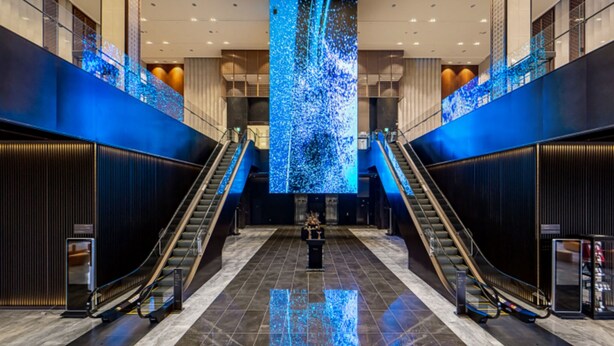 A modern lobby with two escalators, a large digital display, and a marble floor. - Jeonju The May Hotel (Jeonju)