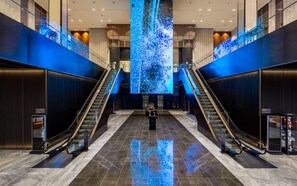 A modern lobby with two escalators, a large digital display, and a marble floor. - Jeonju The May Hotel (Jeonju)