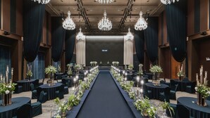 A banquet hall with a central aisle, tables on either side, and chandeliers. - Jeonju The May Hotel (Jeonju)