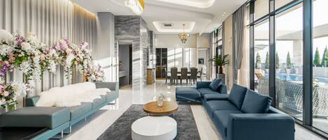 A modern living room with a sofa, a coffee table, and a dining area in the background.