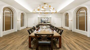 A spacious conference room with a long wooden table, multiple chairs, and a chandelier.