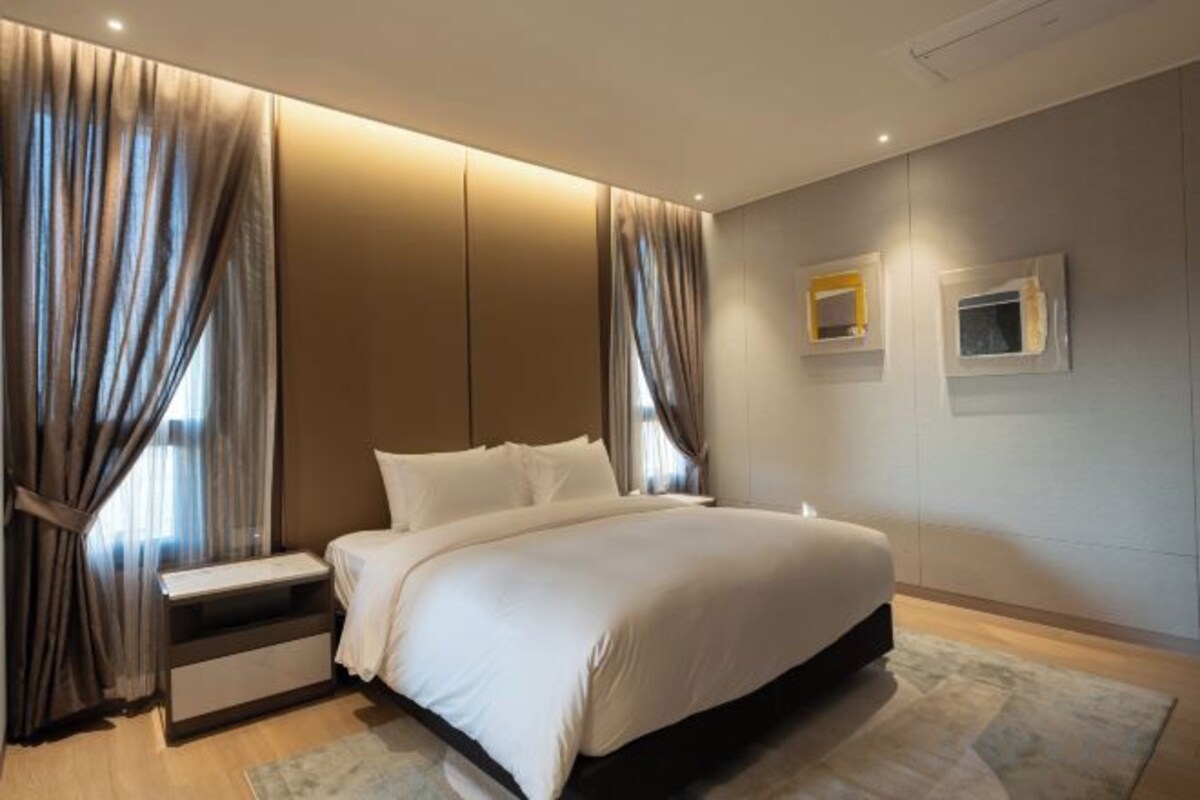 A modern bedroom with a large bed, bedside tables, and curtains.