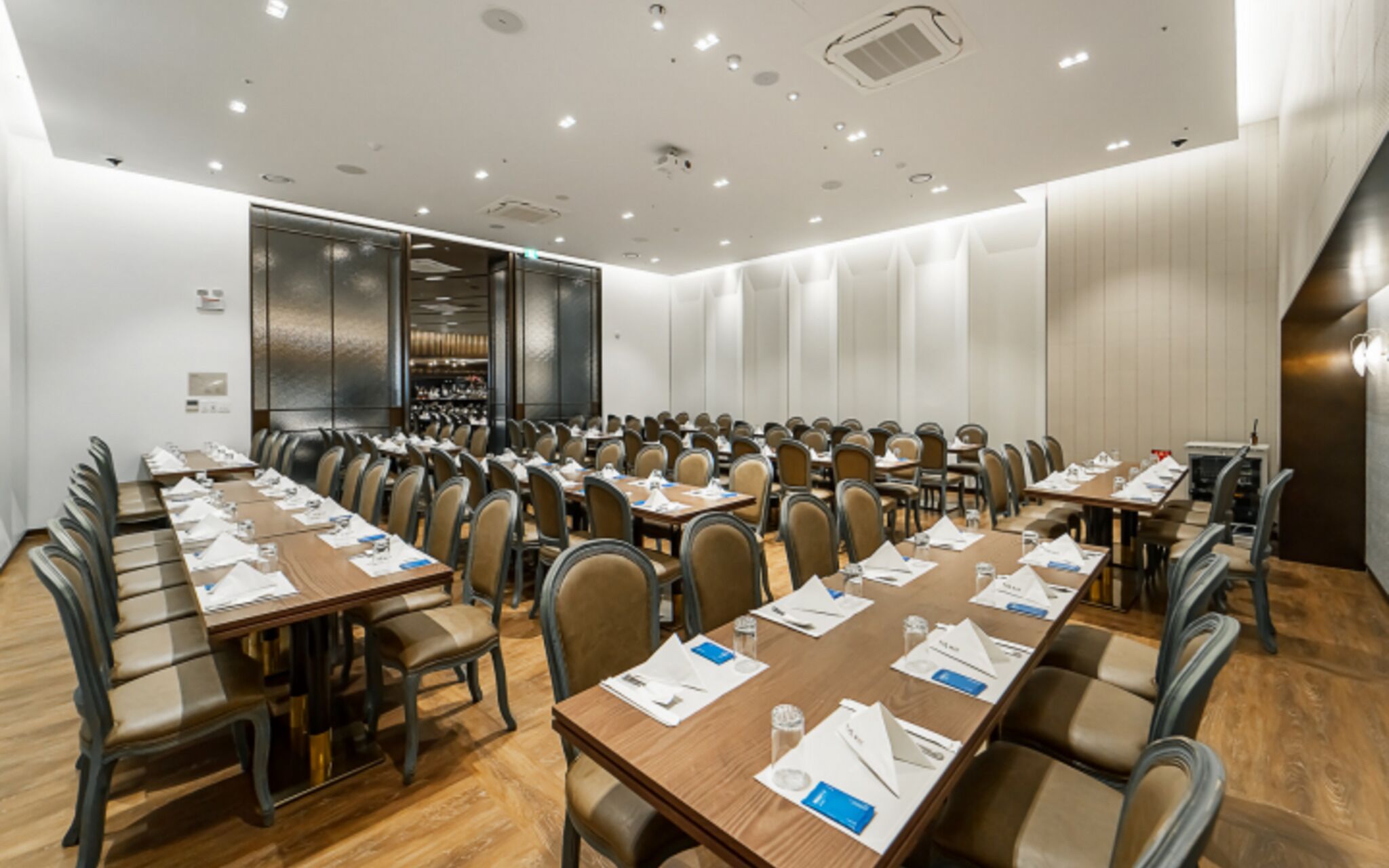 Un salón de conferencias con largas mesas y sillas, equipado con tarjetas de identificación y botellas de agua.