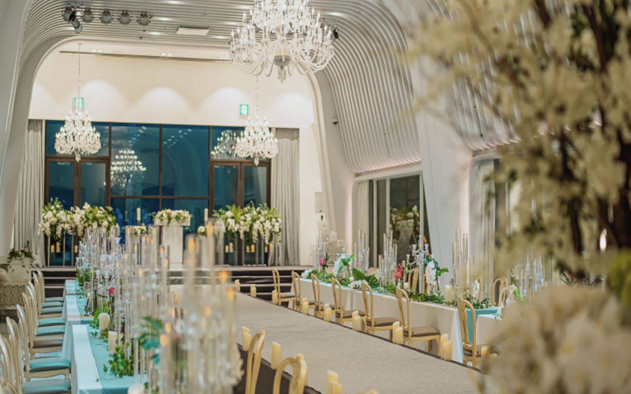 Un salón de banquetes con mesas largas, candelabros y arreglos florales.
