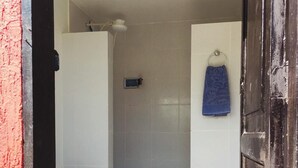 A bathroom with a toilet, a shower, and a blue towel hanging on the wall. - JP Estudio (RJ)