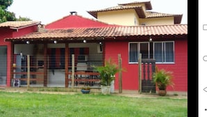 A red house with a tiled roof, a fenced porch, and potted plants. - JP Estudio (RJ)