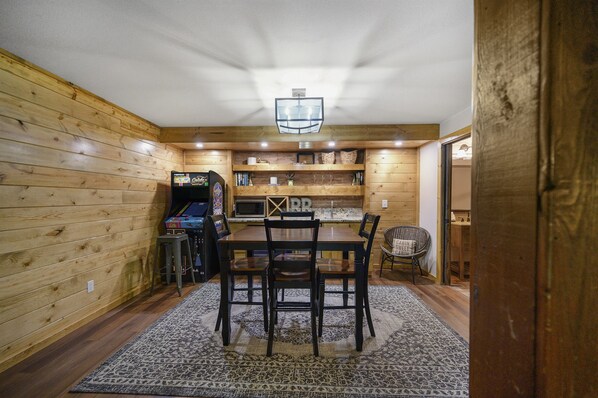 A cozy dining area with a wooden table and chairs, a patterned rug, and a ceiling light fixture.