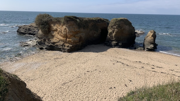 Un paisaje costero con grandes formaciones rocosas y una playa de arena.
