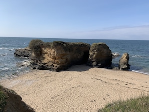 Un paysage côtier caractérisé par de grandes formations rocheuses et une plage de sable.