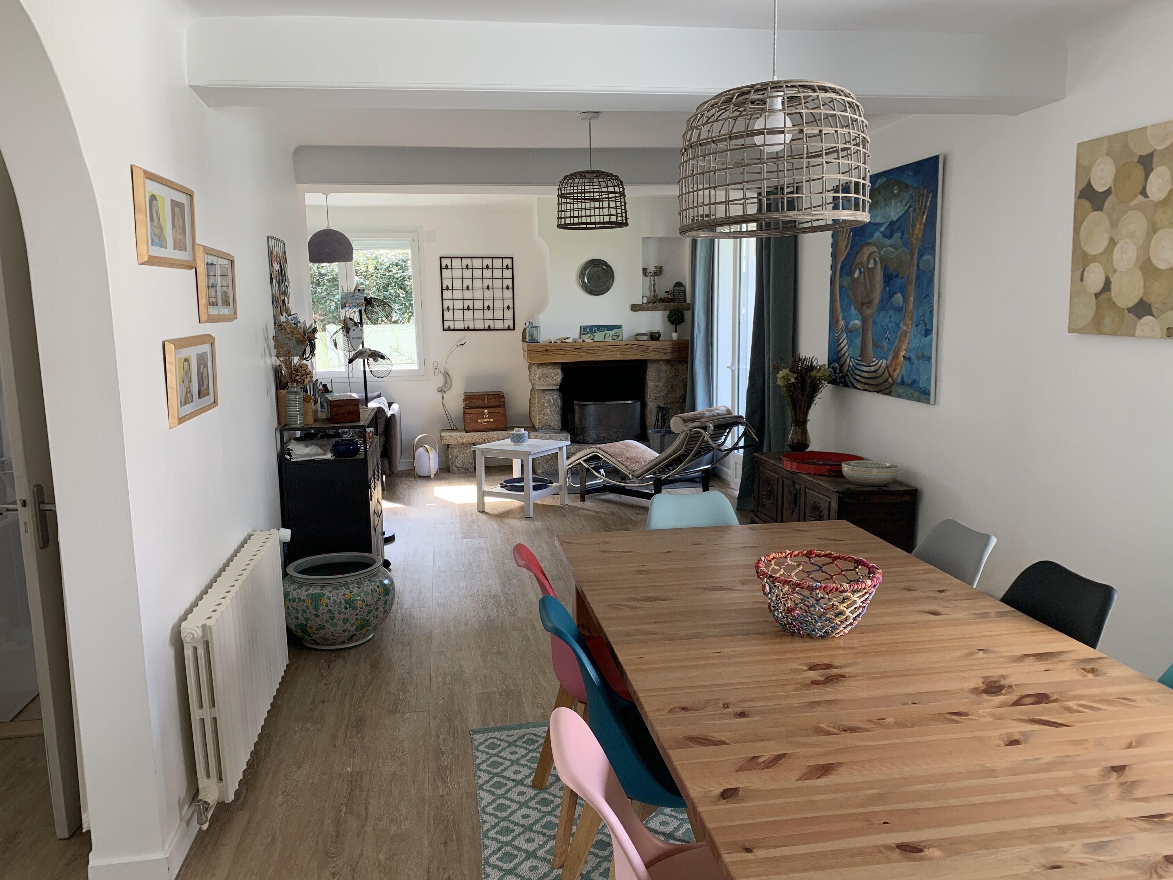 Un vaste espace de vie comprenant une table à manger en bois, une cheminée et une vue sur l’extérieur.