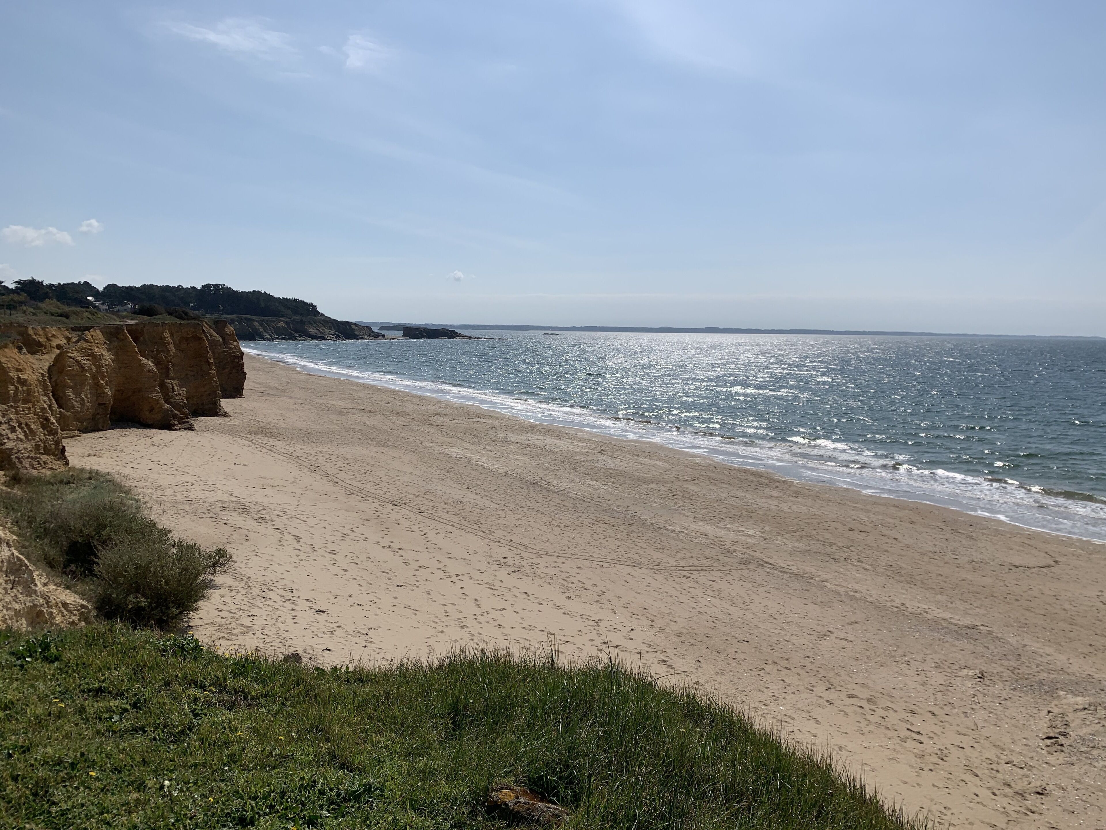 A sandy beach with cliffs and a clear sky.