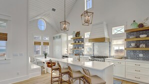 A spacious kitchen with a large island, white cabinetry, and a view of the ocean.