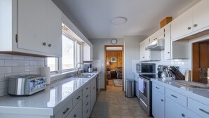 A modern kitchen with white cabinets, a stainless steel toaster, a sink, and a stove. - Mountain View Getaway (West Cornwall)