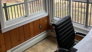 A room with a view of a wooded area through large windows, a black office chair, and a radiator. - Mountain View Getaway (West Cornwall)