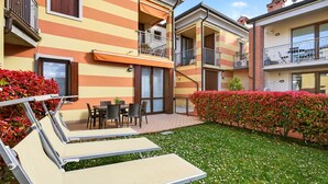 Un immeuble résidentiel doté de balcons, d’un patio avec mobilier d’extérieur et d’un jardin bien entretenu.