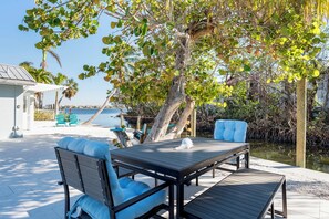 Relax in a serene outdoor setting with a wooden table and two cushioned chairs.