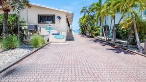Une propriété située en bord de mer, dotée d’une promenade dallée, de palmiers et d’un bâtiment équipé d’une antenne parabolique et d’un climatiseur.