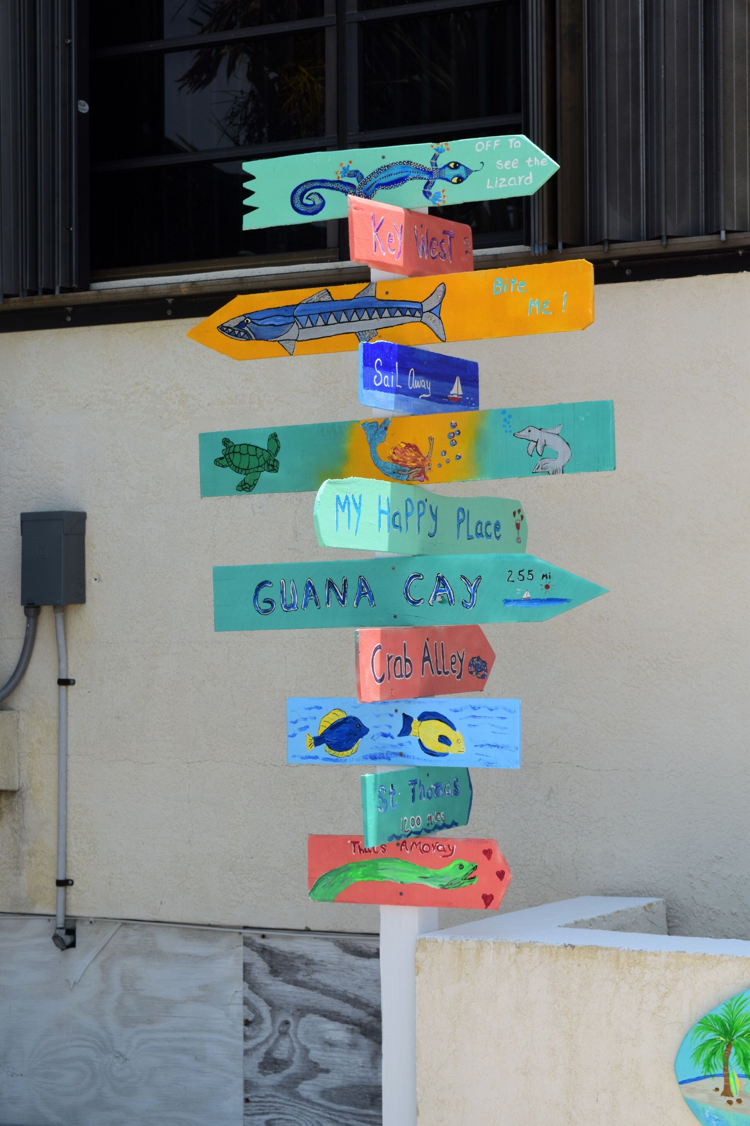 A wall with colorful signs pointing to various locations.