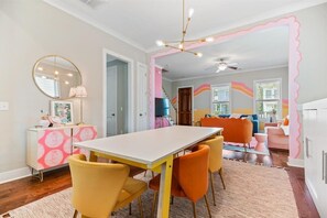 A dining area with a white table, yellow chairs, and a pink patterned cabinet.