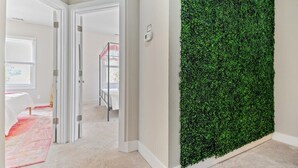 Passadís amb paret vertical de jardí verd, sòls amb moqueta i portes blanques que donen a altres habitacions.