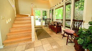 A staircase leading to a door, a wooden bench, a chair with a cushion, and a potted plant. - Large house on beautiful lake, adjoins Sleeping Bear Dunes National Lakeshore (Empire)