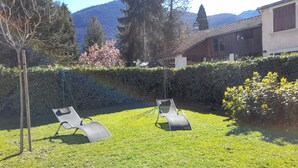 Un giardino sul retro con due poltrone, un prato curato e vista sulle montagne sullo sfondo.