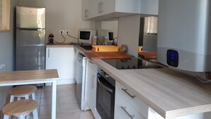 Una cucina moderna con frigorifero in acciaio inossidabile, forno a incasso, microonde e piano di lavoro in legno. Sono presenti due sgabelli all'isola della cucina.