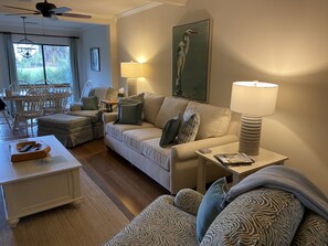 Un salon avec un canapé, une table basse, une lampe et un tableau au mur.