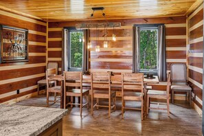 Ein Holzblockhaus-Interieur mit Esstisch, Stühlen und einer Küchenzeile.