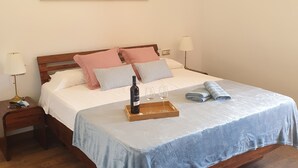 Un dormitorio con una cama de madera, una mesita de noche con una lámpara, un cuadro en la pared y un candelabro.