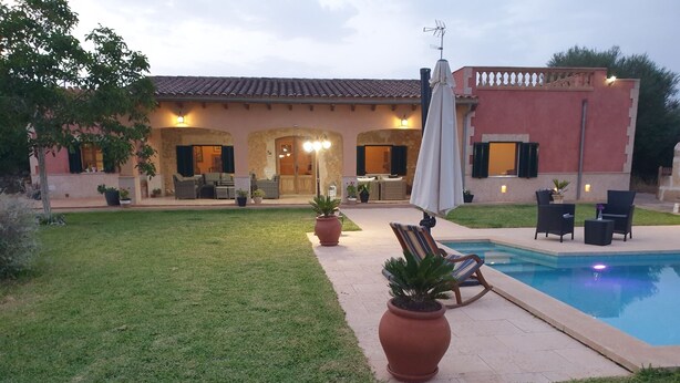 Una casa con piscina, mobiliario exterior y un césped cuidado.