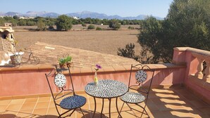 Una terraza con suelo de baldosas, una mesa redonda con sillas y una planta en maceta.
