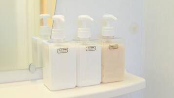 Three bottles of body soap and conditioner on a white shelf.
